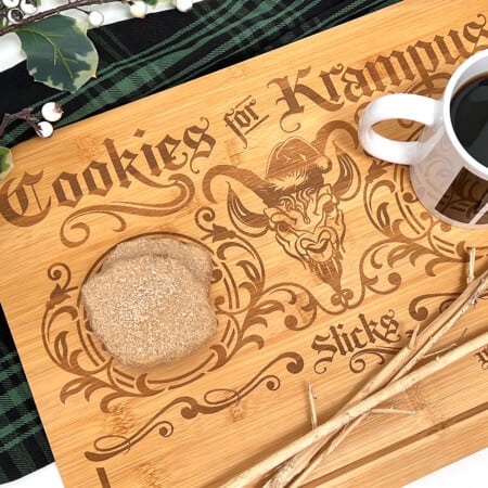A "Cookies for Krampus" wooden cutting board with cookies and a cup of coffee.