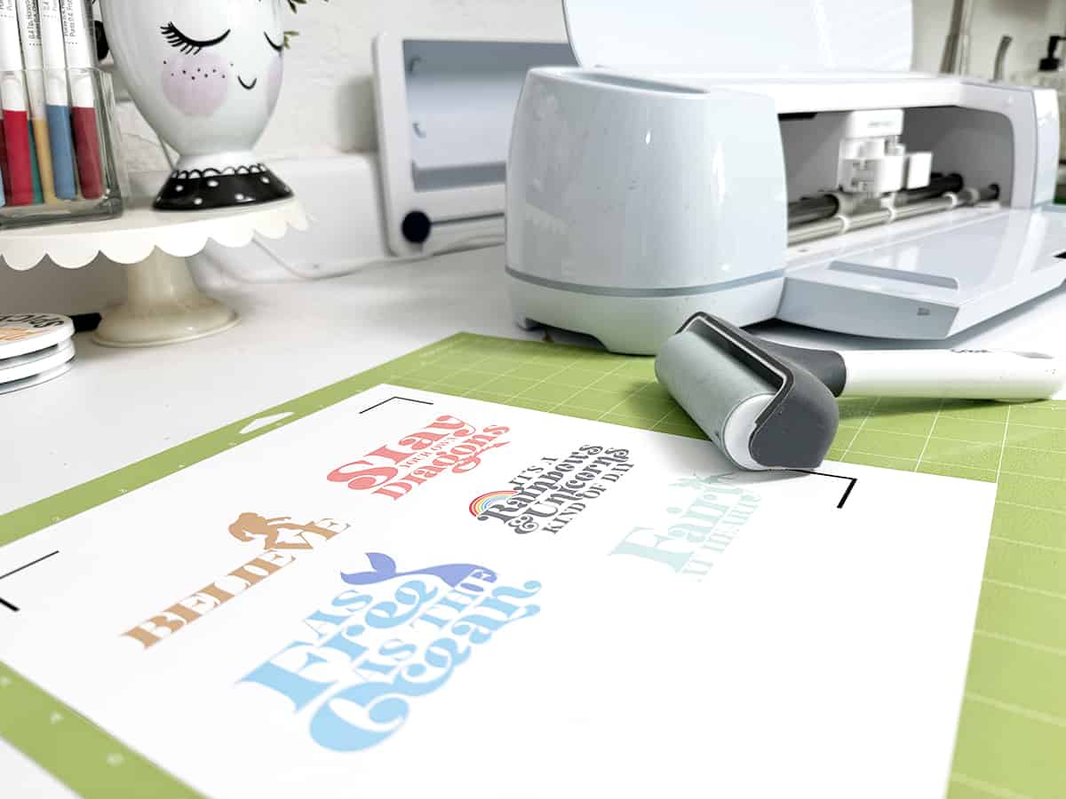 Crafting station with a vinyl cutter and printed material on an adhesive cutting mat.