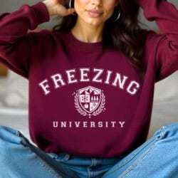 A person wearing a maroon sweatshirt with "Freezing University" and a winter-themed emblem.
