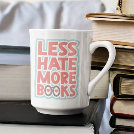 A white mug with the text "Less Hate More Books" in bold sits atop a stack of books, evoking a bookish charm reminiscent of a cozy reading nook.