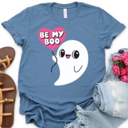 A blue t - shirt with a ghost holding a heart balloon and saying be my boo.