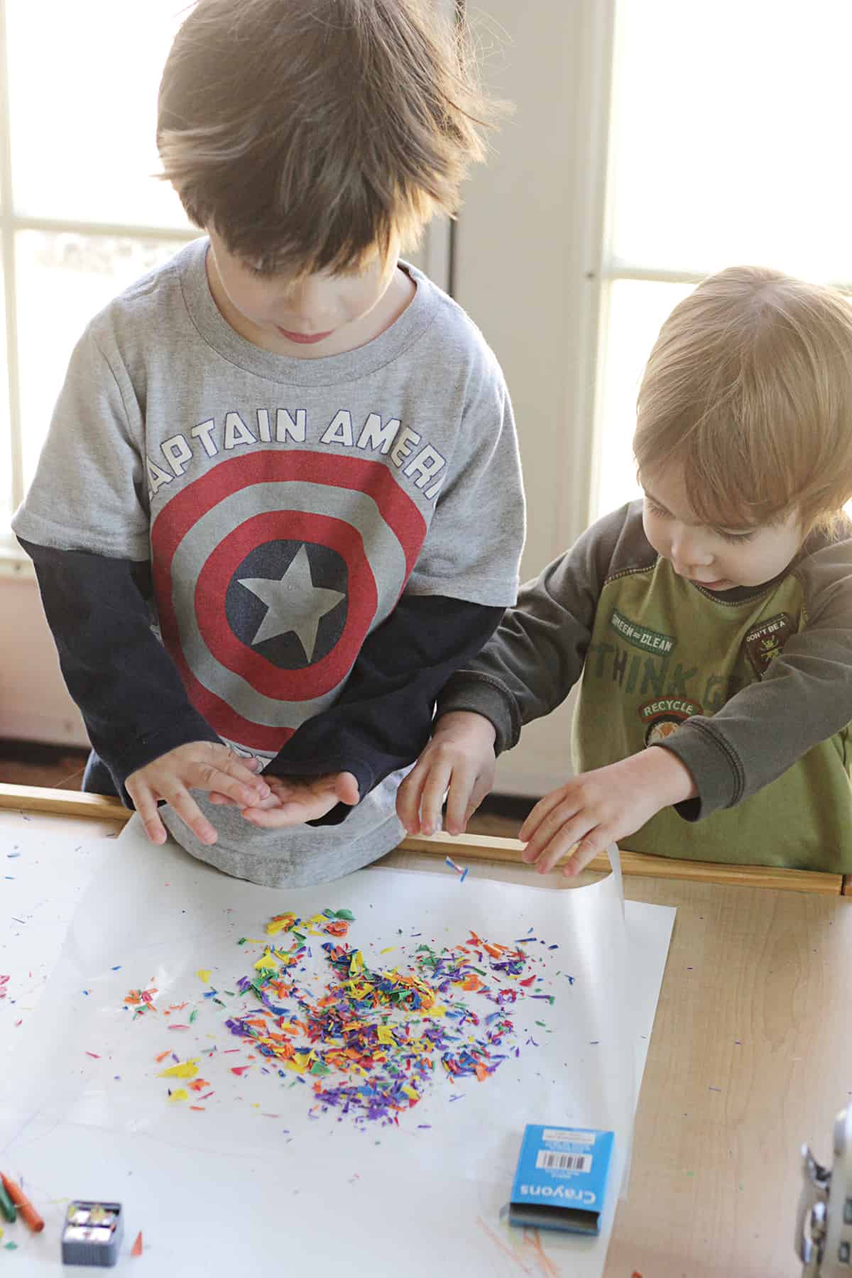 Two kids playing with sprinkles on a table.