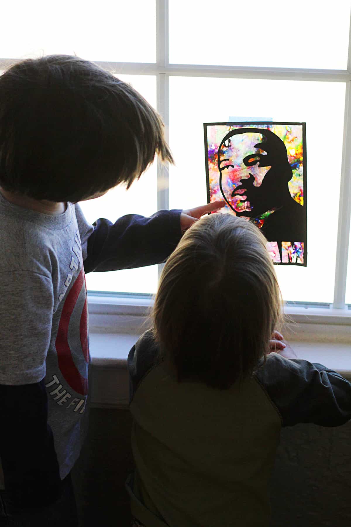 Two kids celebrating Martin Luther King Day by admiring a picture of the iconic civil rights leader.