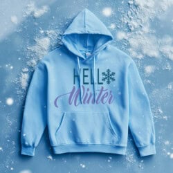 Light blue hoodie with the text "Hello Winter" in green and purple, featuring a snowflake design. The hoodie is displayed on a snowy background.